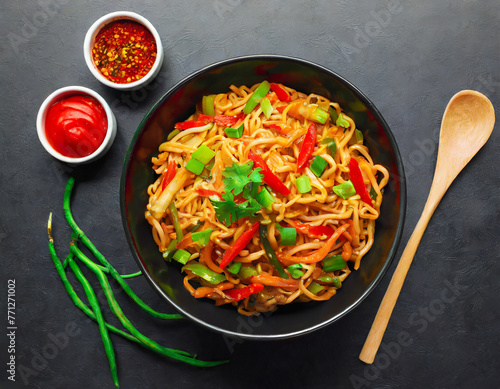 vegetarian schezwan noodles or vegetable hakka noodles or chow mein in black bowl at dark background. schezwan noodles is indo chinese cuisine hot dish with udon noodles, vegetables and chilli sauce