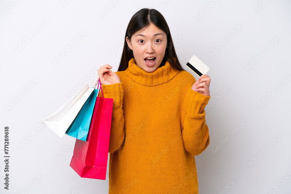 Young Chinese woman isolated on white background holding shopping bags and surprised Young Chinese woman isolated on white background holding shopping bags and surprised