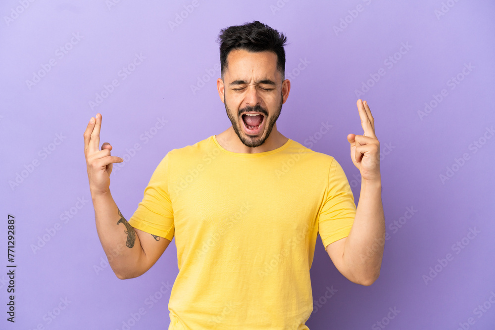 Young caucasian man isolated on purple background with fingers crossing Young caucasian man isolated on purple background with fingers crossing