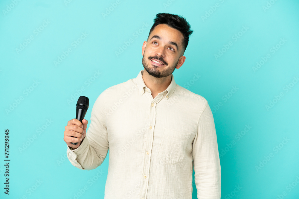 Young caucasian singer man isolated on blue background thinking an idea while looking up Young caucasian singer man isolated on blue background thinking an idea while looking up