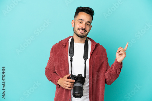 Young photographer caucasian man isolated on blue background showing and lifting a finger in sign of the best