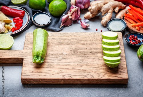 Fototapeta Naklejka Na Ścianę i Meble -  Food and cooking background. Gray table with chopped zucchini. Paprika, vegetables, spices and ingredients for cooking vegan Asian dishes with ginger, garlic, soy sauce, top view