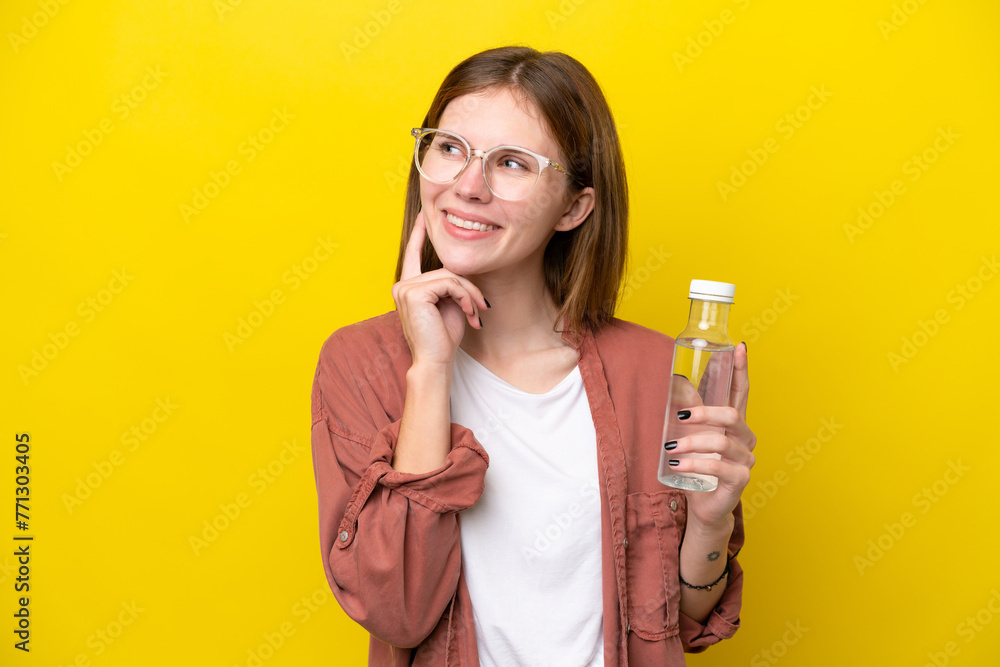 Young English woman with a bottle of water isolated on yellow background thinking an idea while looking up Young English woman with a bottle of water isolated on yellow background thinking an idea while looking up