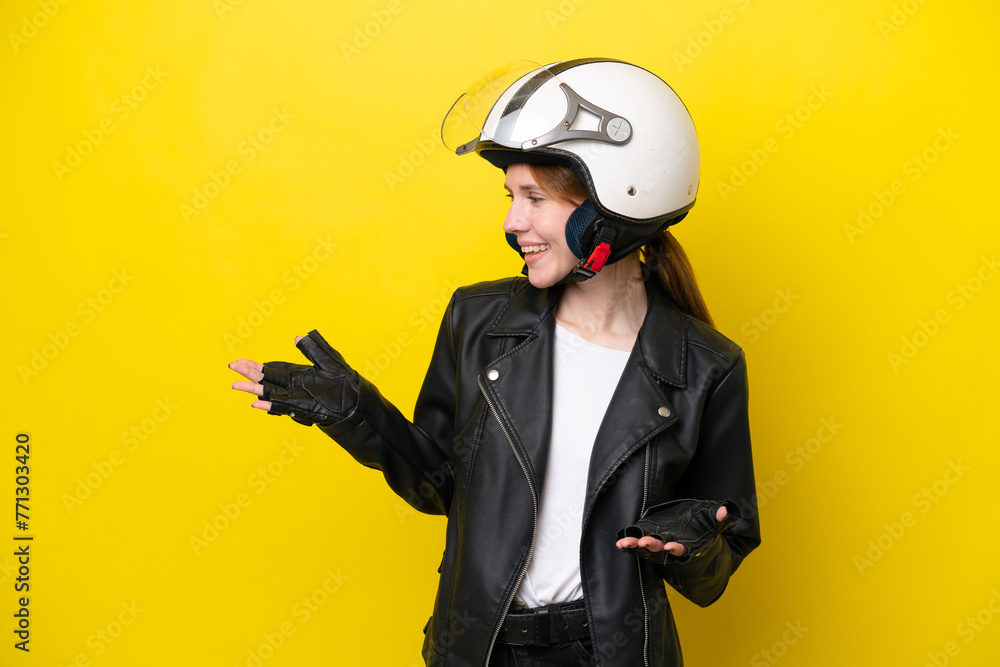 Young English woman with a motorcycle helmet isolated on yellow background with surprise expression while looking side Young English woman with a motorcycle helmet isolated on yellow background with surprise expression while looking side