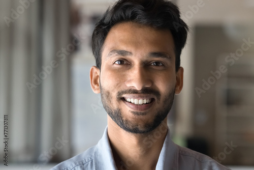 Happy attractive young Indian man close up portrait. Face of positive handsome guy looking at camera with toothy smile. Cheerful handsome male model in casual head shot. Video call screen view