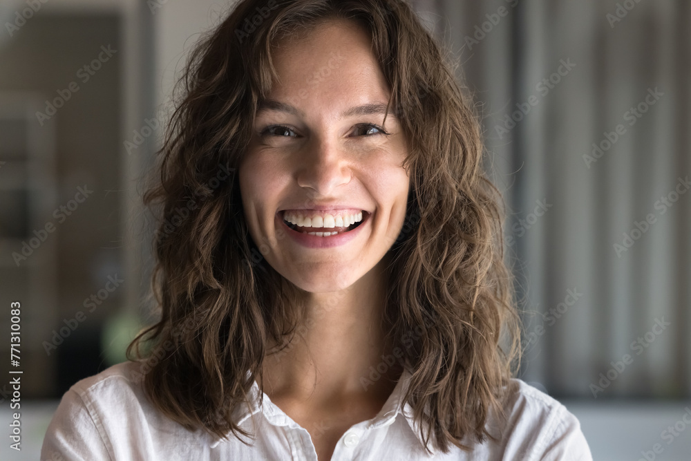 Happy attractive young Caucasian woman with wavy hair looking at camera with toothy smile, laughing, posing for front close up portrait. Cheerful successful professional girl video call head shot - obrazy, fototapety, plakaty 