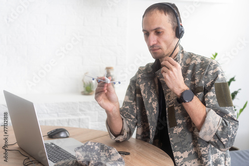 Military Technical Service, Air Force Concept. Hands of a man in uniform holding a silver toy airplane. A middle-aged adult man in a green camouflage uniform. Indoors. 