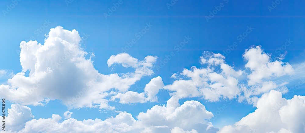 White fluffy clouds are scattered across the clear blue sky above calm waters, creating a serene and peaceful scenery