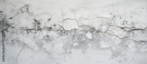 A close-up of a white wall showing signs of wear with peeling and cracked gray paint in a black and white color scheme