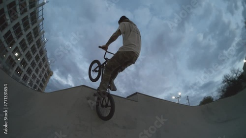 BMX biker tweaking huge air out of skatepark bowl at sunrise, fisheye follow at 800fps extreme slowmo photo