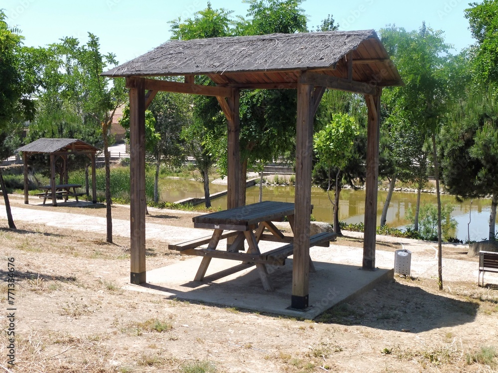 Typical picnic area with a wooden table and bench and a shade roof in Spain
