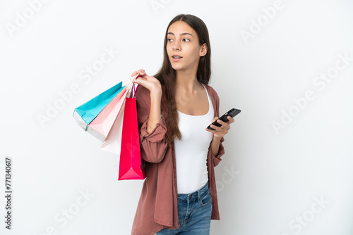 Young French girl isolated on white background holding shopping bags and a mobile phone