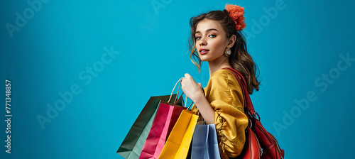 woman holding shopping bags on blue background in the s 2932bfb1-a17c-45dc-bc9b-aefbbdbedf36