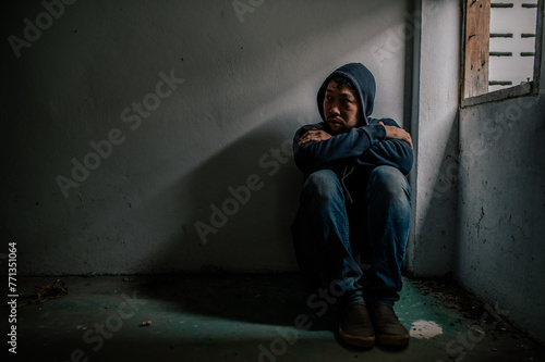 Asian man addict drug in the deserted place,A junkie feels alone in this world,Sad young man sitting in the corner of the room,People are stressed and have depression