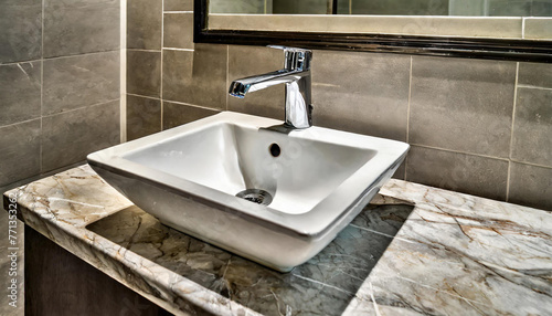 A white square sink is placed atop a bathroom counter  showcasing modern and clean design. The faucet complements the sink  adding functionality to the space