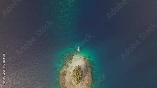 Vertical drone shot from a remote island in San Blas Archipelago with an sailboat anchored on the beach. photo