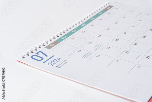 Desk calendar of 2024 laying on white background. July page of 2024 calendar, side view and selective focus shot. 