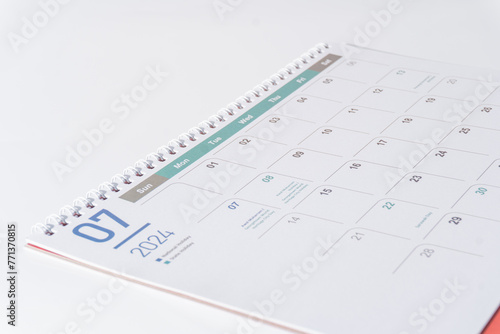 Desk calendar of 2024 laying on white background. July page of 2024 calendar, side view and selective focus shot. 