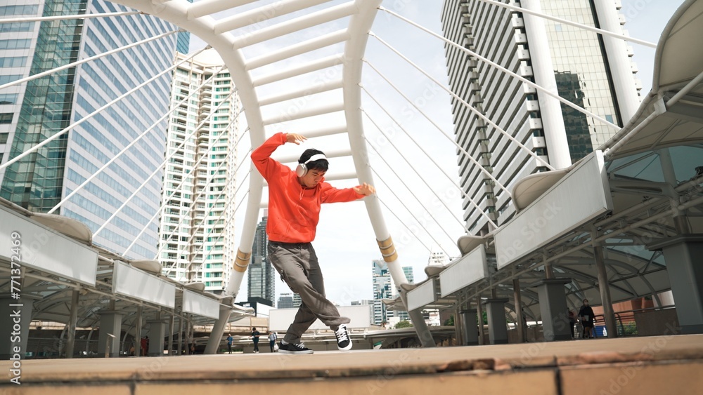 Asian hipster wearing headphone show footstep while jumping at city. Professional break dancer perform b-boy dancing performance at city. Break dance or street dance. Outdoor sport 2024. Sprightly.