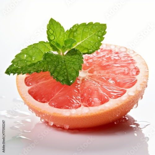 Half a wet pink grapefruit with green mint leaves on top photo