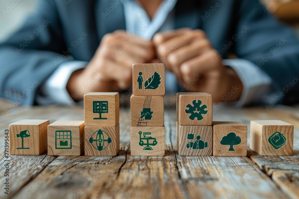 Obraz premium A businessman surrounded by cascading wooden blocks with green eco friendly icons.