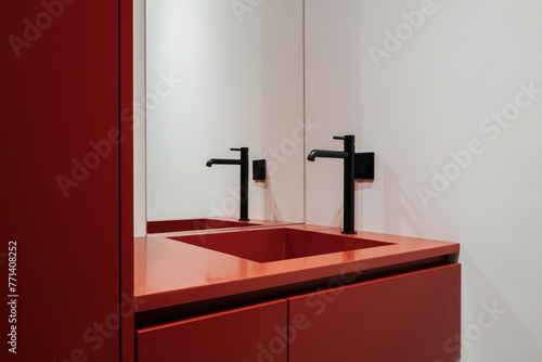 A bathroom with red cabinetry, a sink, and a mirror