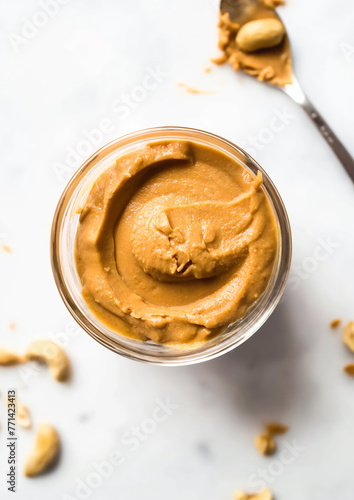 Top view of creamy peanut butter in a transparent glass bowl on a white background