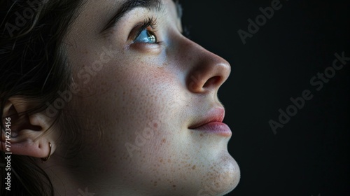 sideview portrait of a young woman looking up on a black studio background