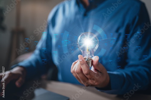 brainstorming, future, genius, imagination, intelligence, invention, leadership, learning, plan, strategy. A man is holding a light bulb. The light bulb is surrounded, giving it a futuristic.