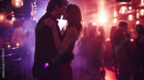 Stylish and beautiful young romantic lovely couple dancing in nightclub, motion blur selective focus reportage flash photography style. Sparkles and glimmers for glamour and excitement atmosphere.