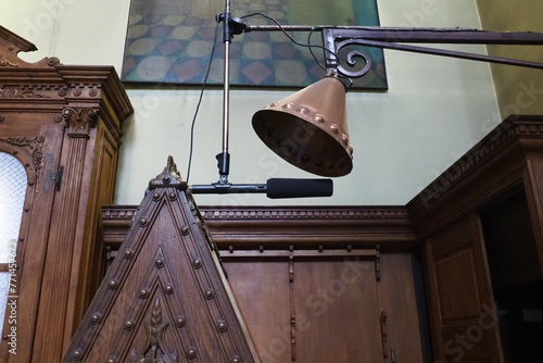 Equipment for prayer and ceremonial chants in Christian Orthodox Church. Microphone on stand, antique bronze earpiece with rivets, wood cabinets, boiserie panels. Kotor Montenegro Church St. Nicholas.