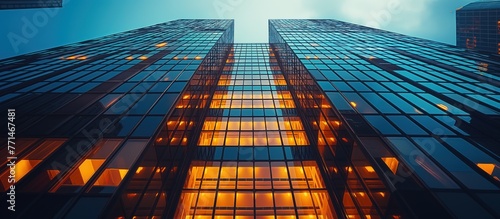 A tall building with many windows and a bright blue sky. The building is lit up with lights, giving it a warm and inviting atmosphere