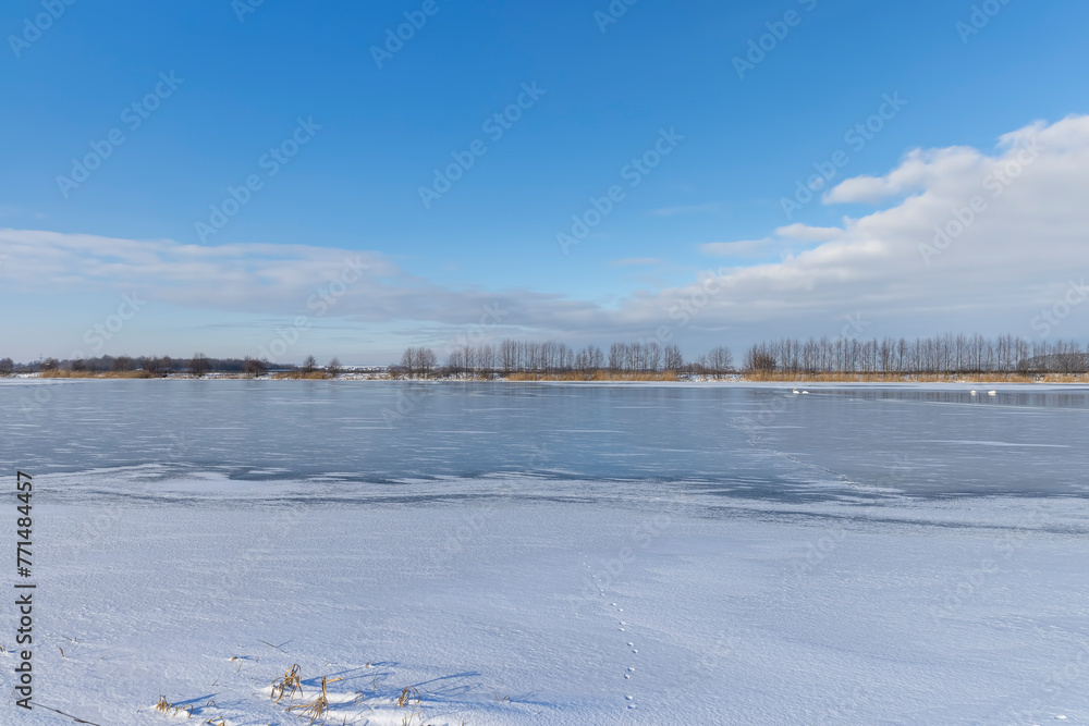 Fototapeta premium the lake is covered with ice in winter and sunny weather
