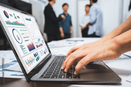 Analyst team uses BI Fintech on a laptop to analyze financial data on blurred background. Business people analyze BI dashboard for insights power into business marketing planning. Prudent