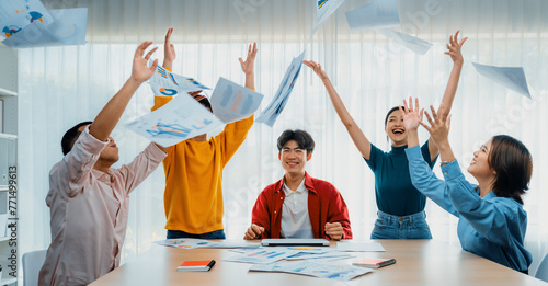 Excited and happy startup company employee celebrate and throw paper in the air after make successful business. Teamwork and positive environemtn create productive and supportive workplace. Synergic photo