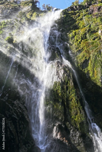 Stunning view of a waterfall cascading down a mountain cliff in Fjordland South Island  New Zealand.