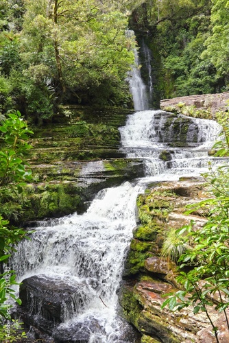 Fototapeta Naklejka Na Ścianę i Meble -  Scenic waterfall cascading through a natural setting of trees and rocks. New Zealand.