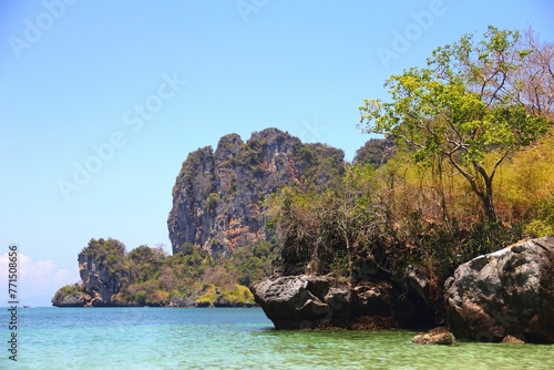 Tranquil sea with a rocky shoreline and lush vegetation. Railay Beach, Thailand.