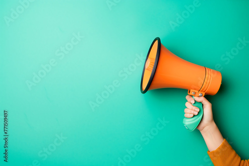 Hand holding megaphone on blue background with copy space.