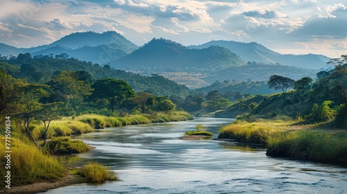 A serene river calmly meanders through a picturesque landscape with lush greenery and distant mountains under a soft sky