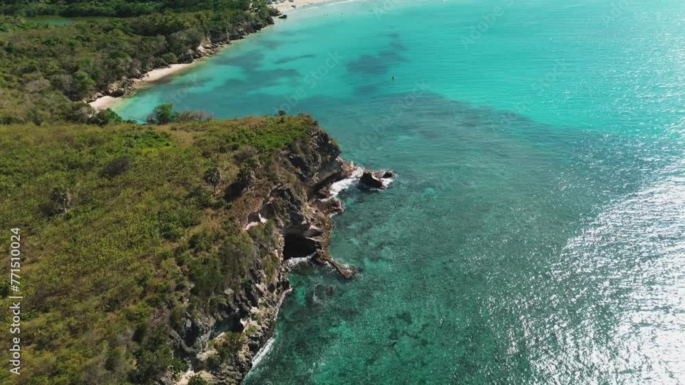 Colorful waters of the ocean, swirl around the rocky and scenic coastline. Sea waves breaking over rocks. Ttropical island. Turquoise ocean. Caribbean Sea. Flying forward. Colorful waters of the ocean, swirl around the rocky and scenic coastline. Sea waves breaking over rocks. Ttropical island. Turquoise ocean. Caribbean Sea. Flying forward.