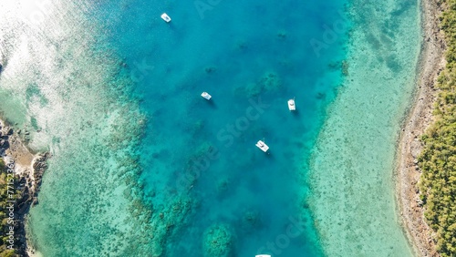Aerial view of several boats peacefully floating in the pristine ocean water.