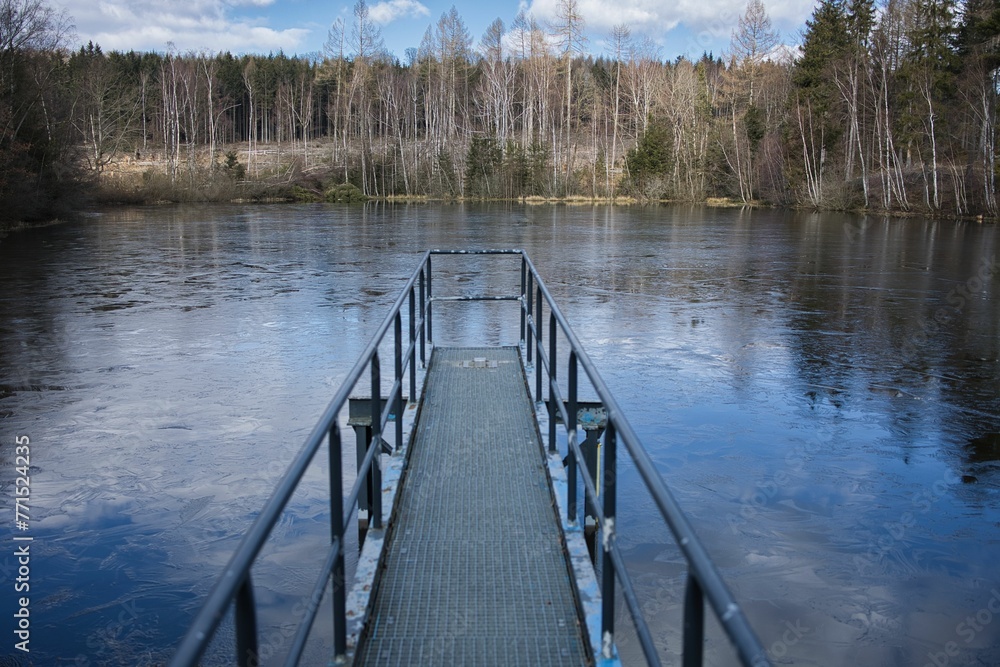 Idyllic scene showcasing a dock situated on a riverbank, surrounded by lush greenery Idyllic scene showcasing a dock situated on a riverbank, surrounded by lush greenery