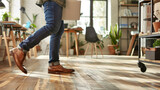 A man is walking across a smooth and polished hard wood floor, each step creating a soft tapping sound