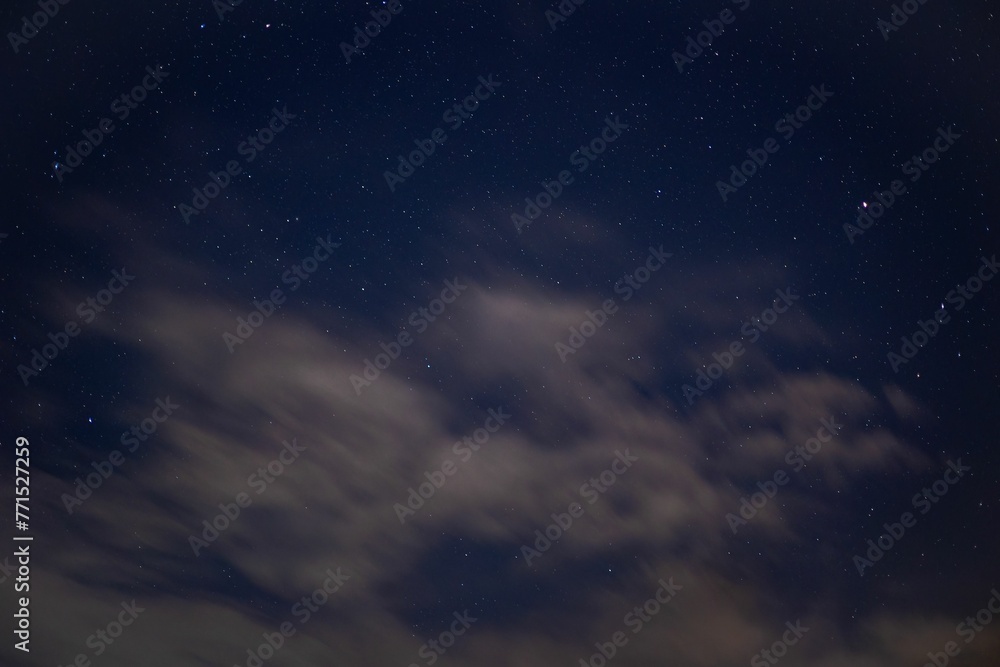 Obraz premium Vibrant blue sky with a line of wispy white clouds and stars