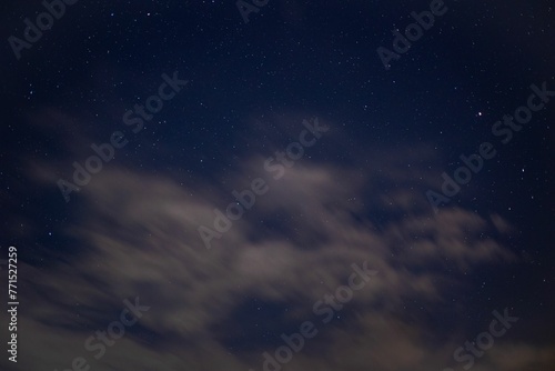 Vibrant blue sky with a line of wispy white clouds and stars