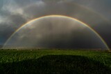 two rainbows with clouds in the background, on grass field