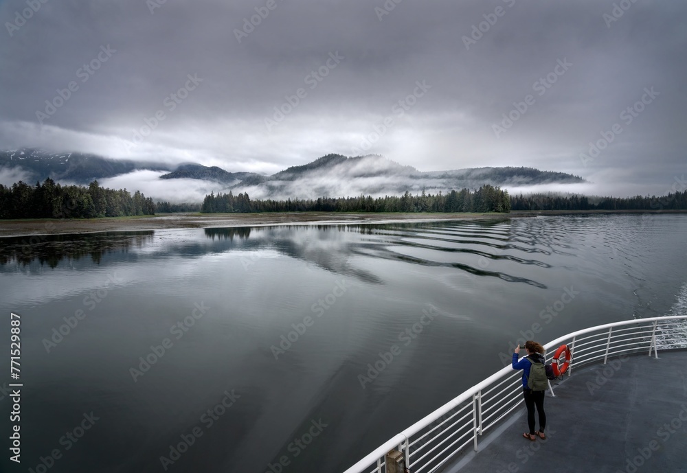 Female photographing the mesmerizing view of the lake with the foggy hills in the distance