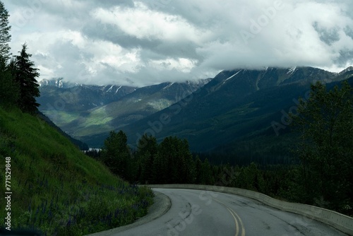 Scenic view of a winding road leading to a valley surrounded by mountains and trees © Wirestock