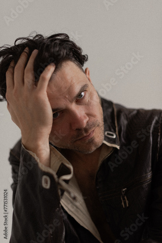 man with headache, man in a leather jacket holding his head with his hand